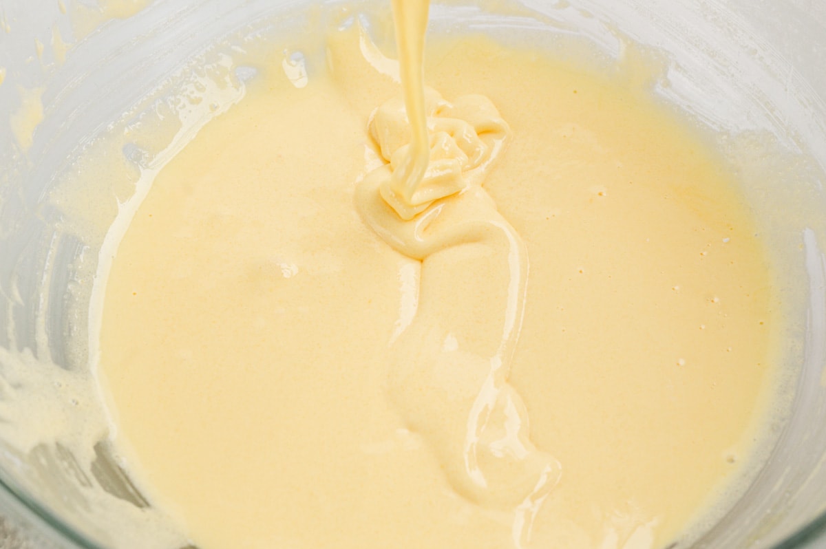 Whisked egg yolks with sugar and cornstarch. Pale yellow mixture in a glass bowl.