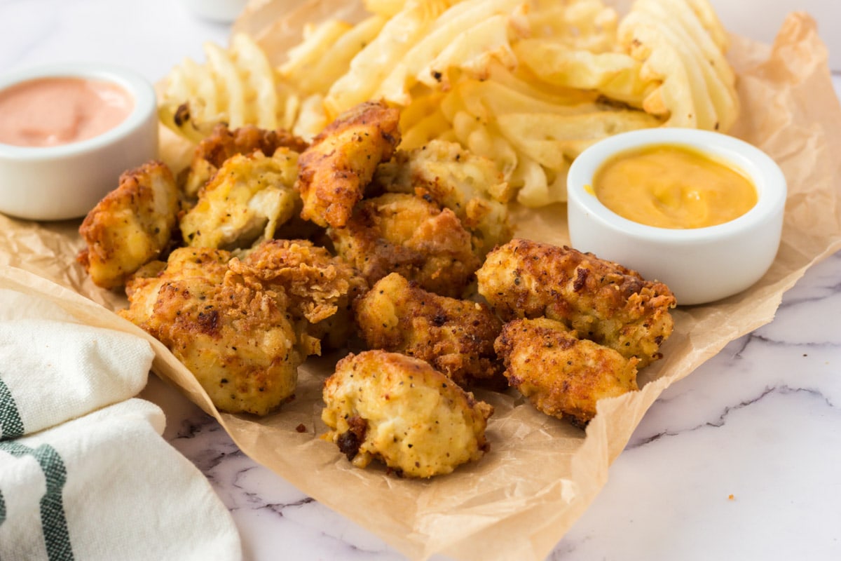 Chicken nuggets and waffle fries on brown paper.