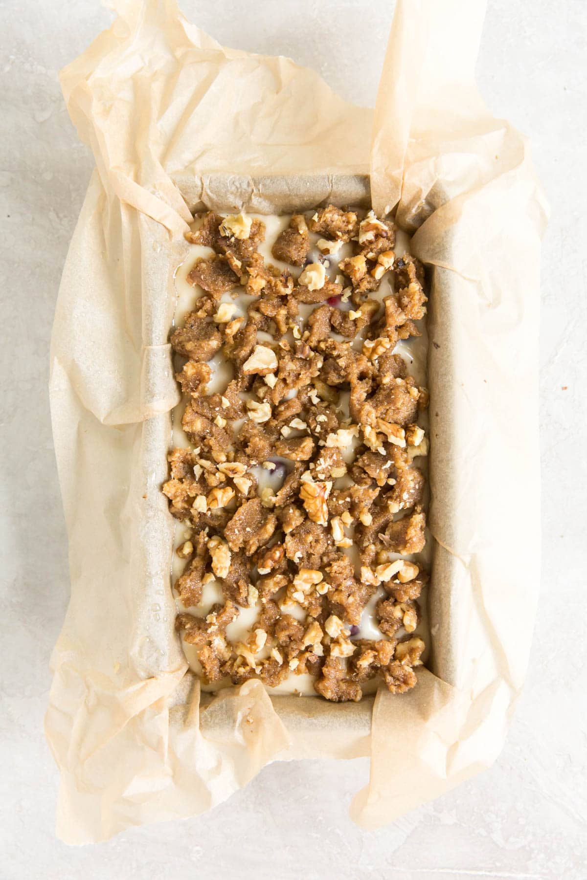 Walnut topped bread batter in a loaf pan.