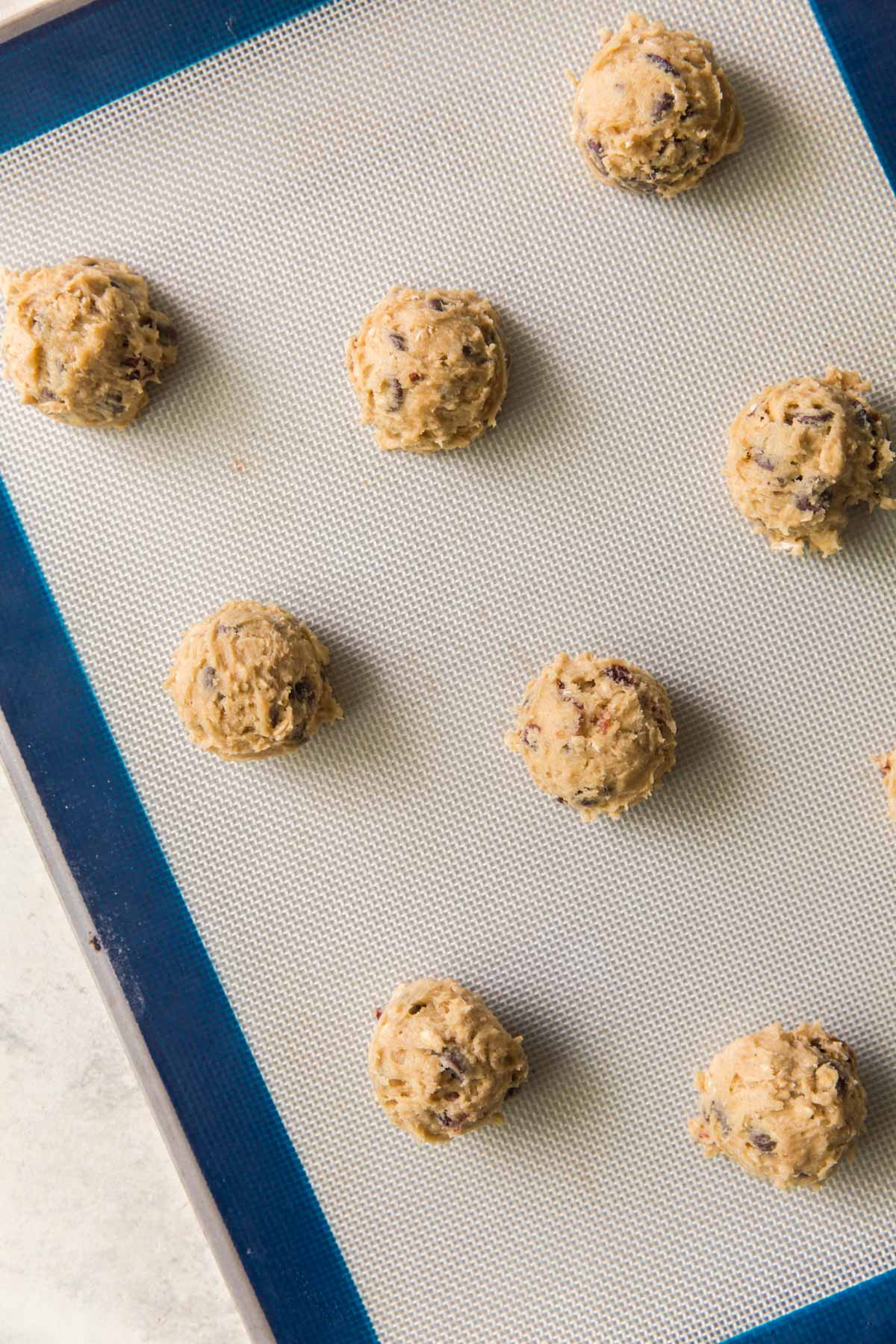 Lined cookie sheet with scoops of cookie dough.