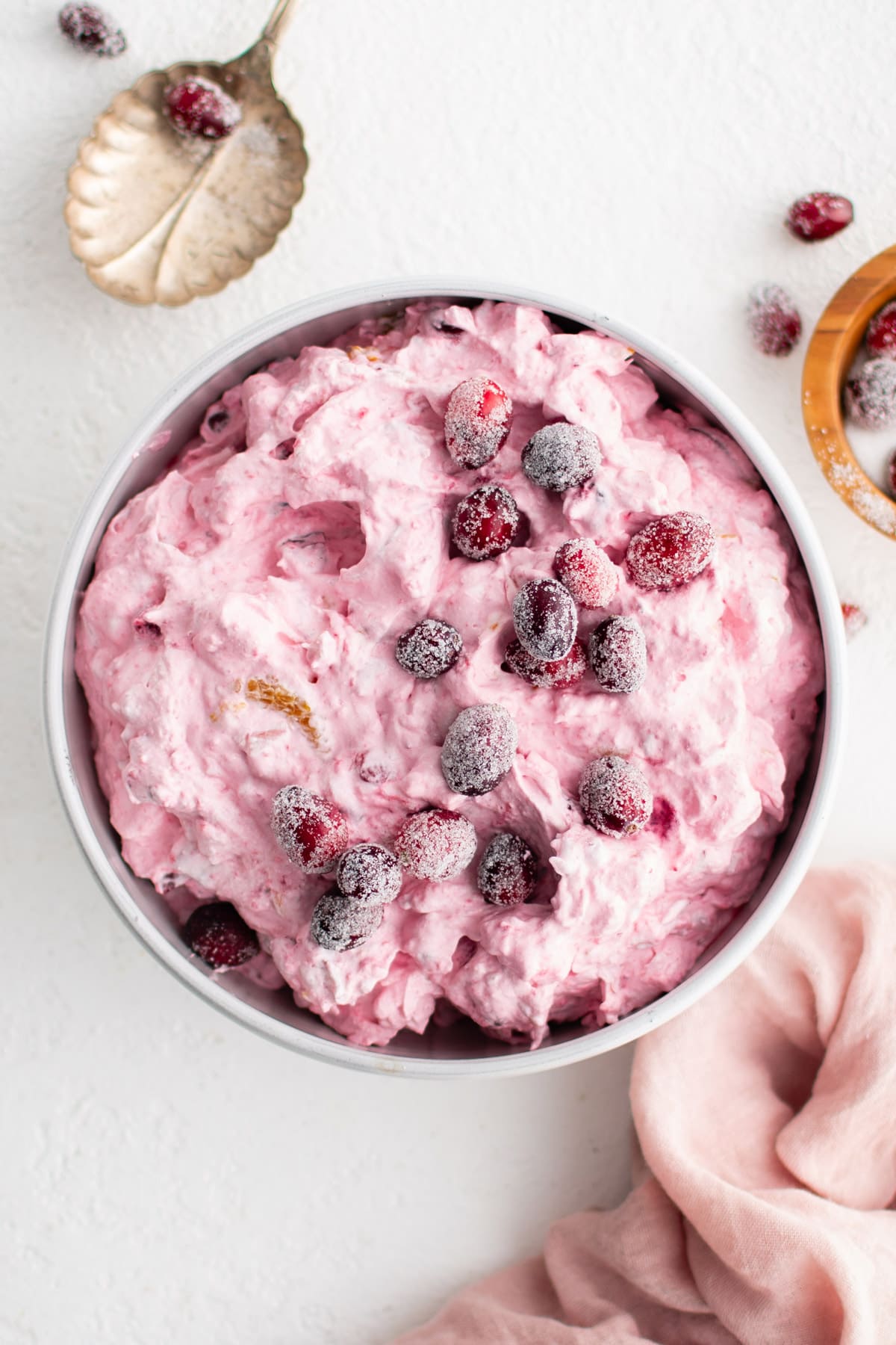 Pink cranberry fluff in a bowl, topped with sugar coated cranberries.
