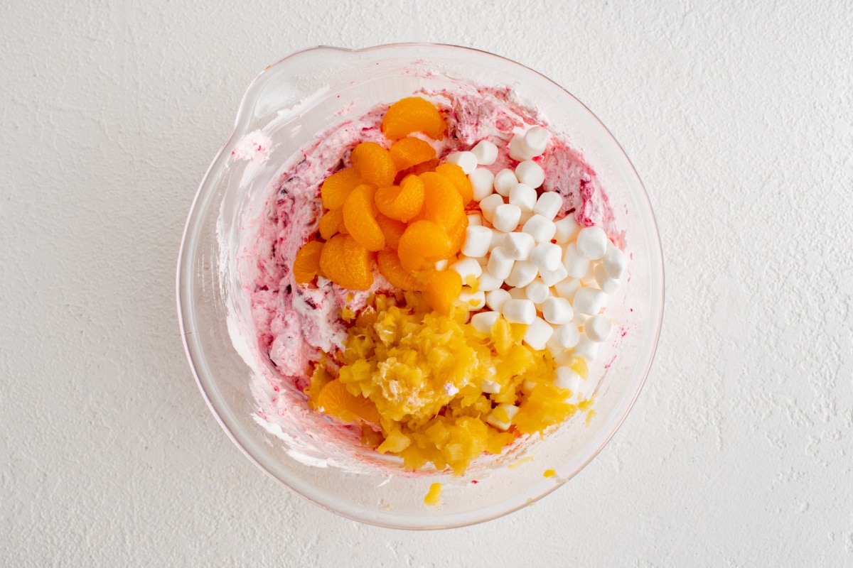 Oranges, marshmallows and pineapples
 in a bowl with pink cranberry sauce