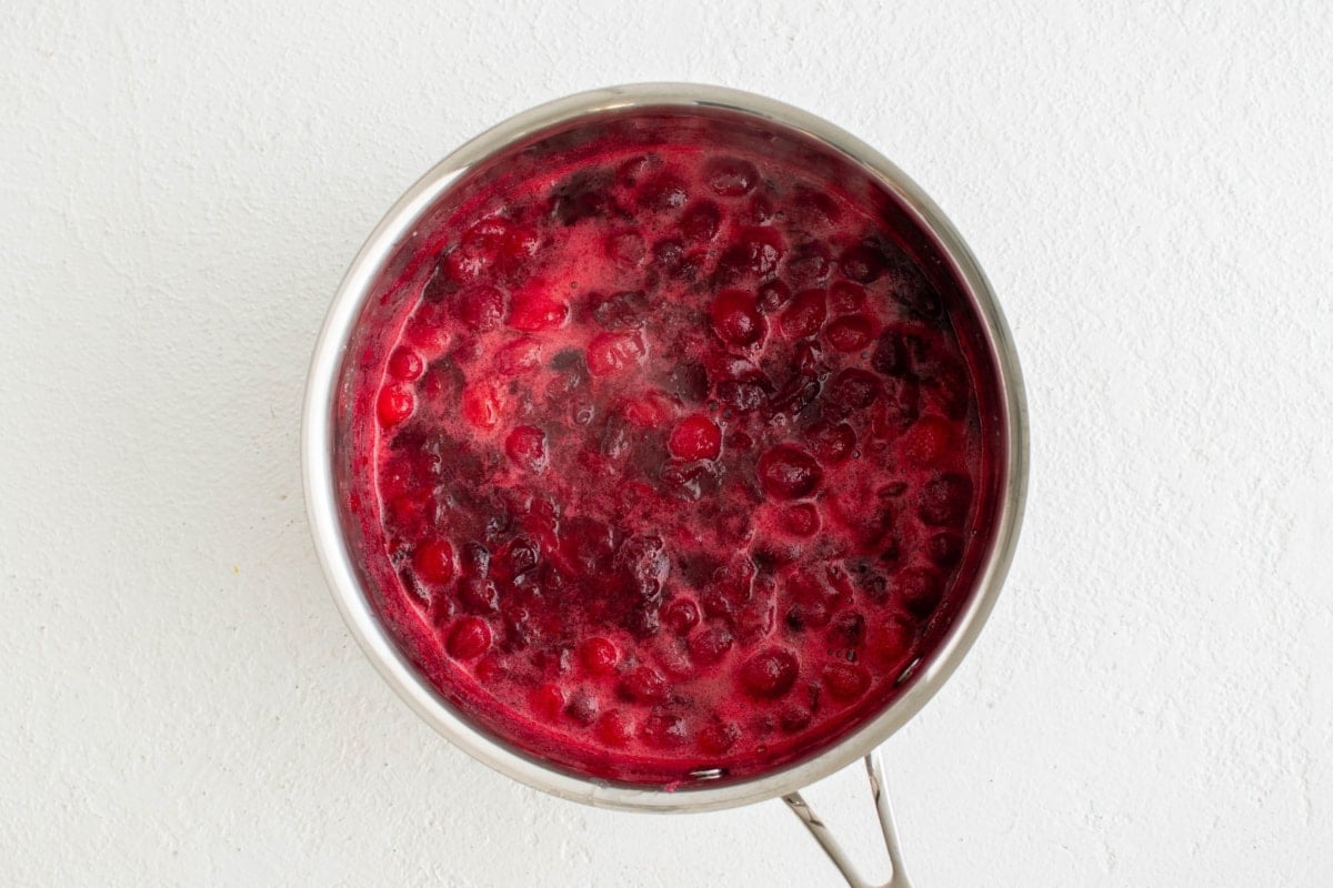 Simmering cranberries, water and sugar in a skillet.