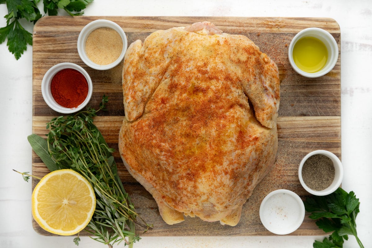 Spices coating a whole chicken on a cutting board