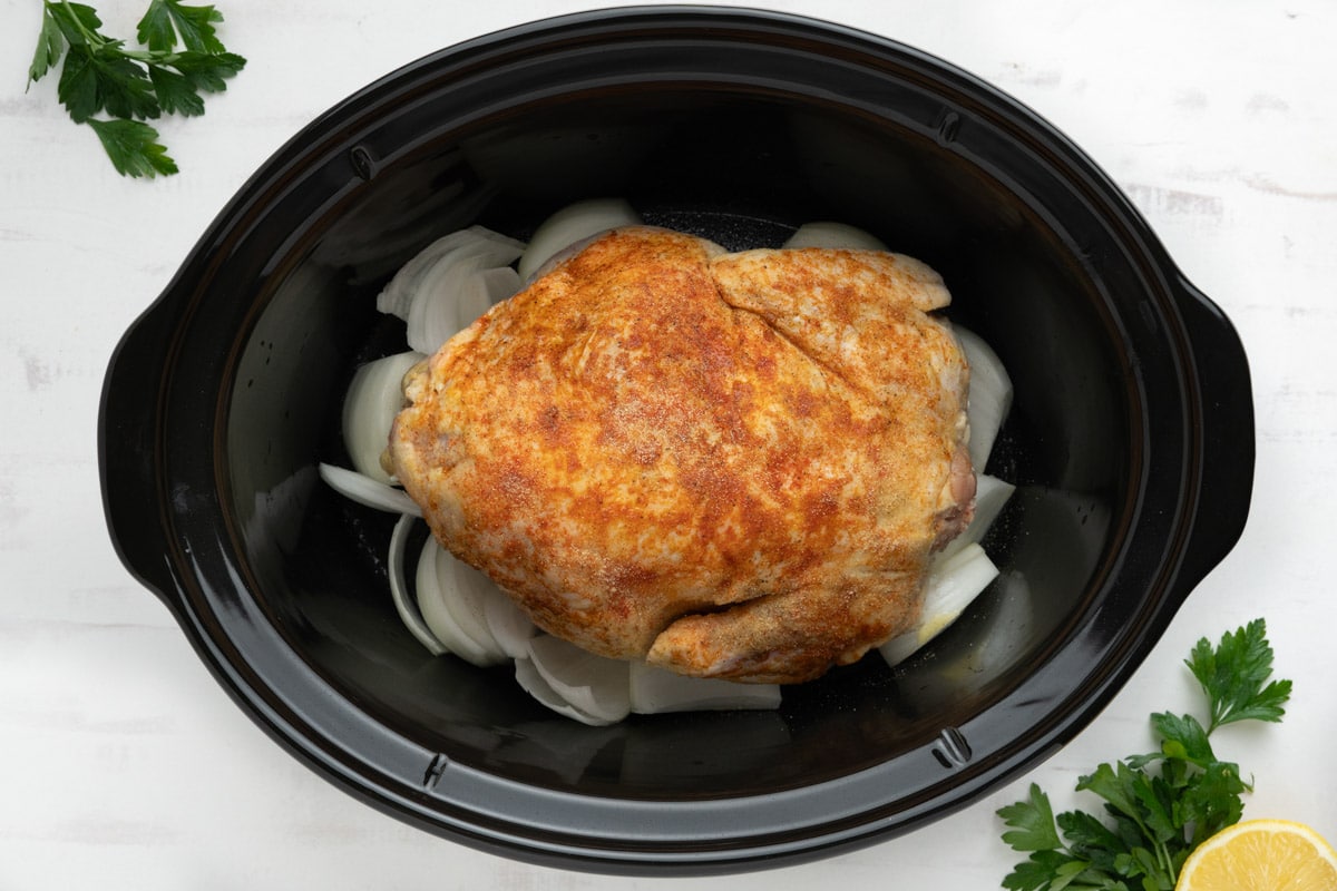 whole chicken on top of onionsl in a crock pot.