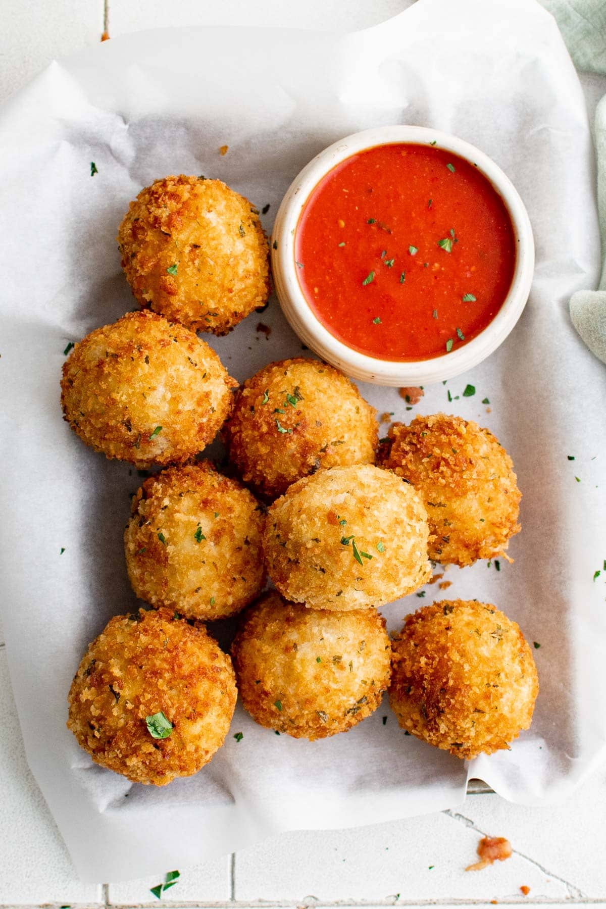 Fried mashed potato balls on a tray with a small dish of marinara sauce.