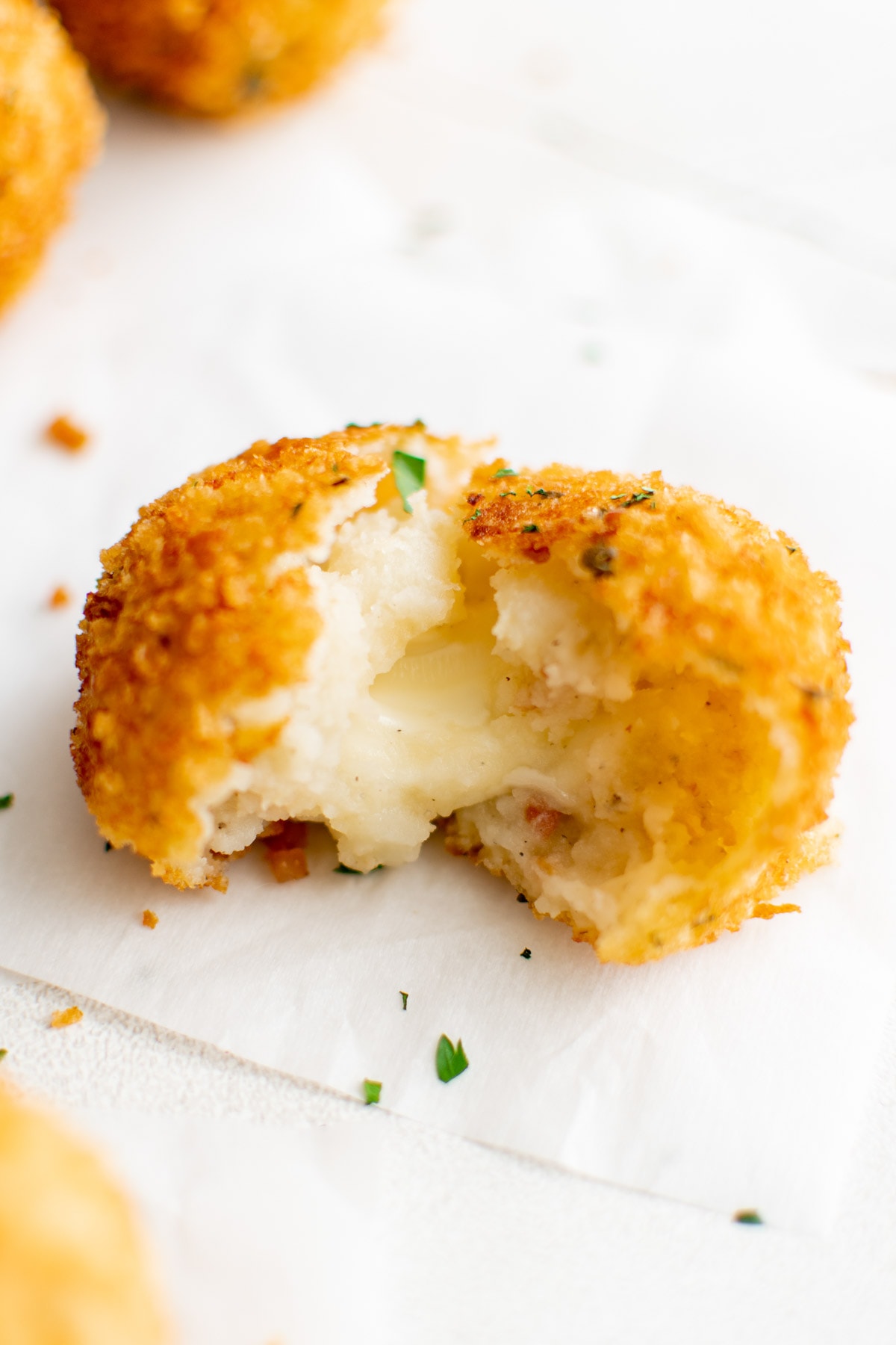 Crispy potato ball with cheese oozing out of it.