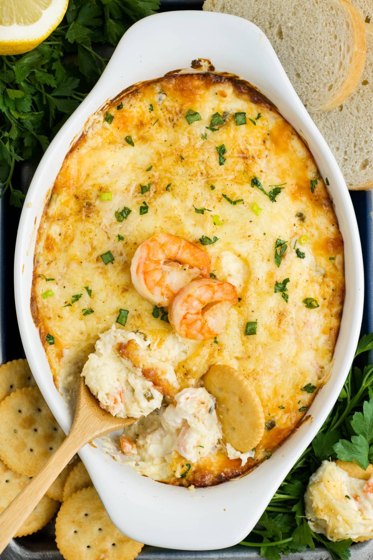 Baked shrimp dip with shrimp on top and a small wooden spoon.
