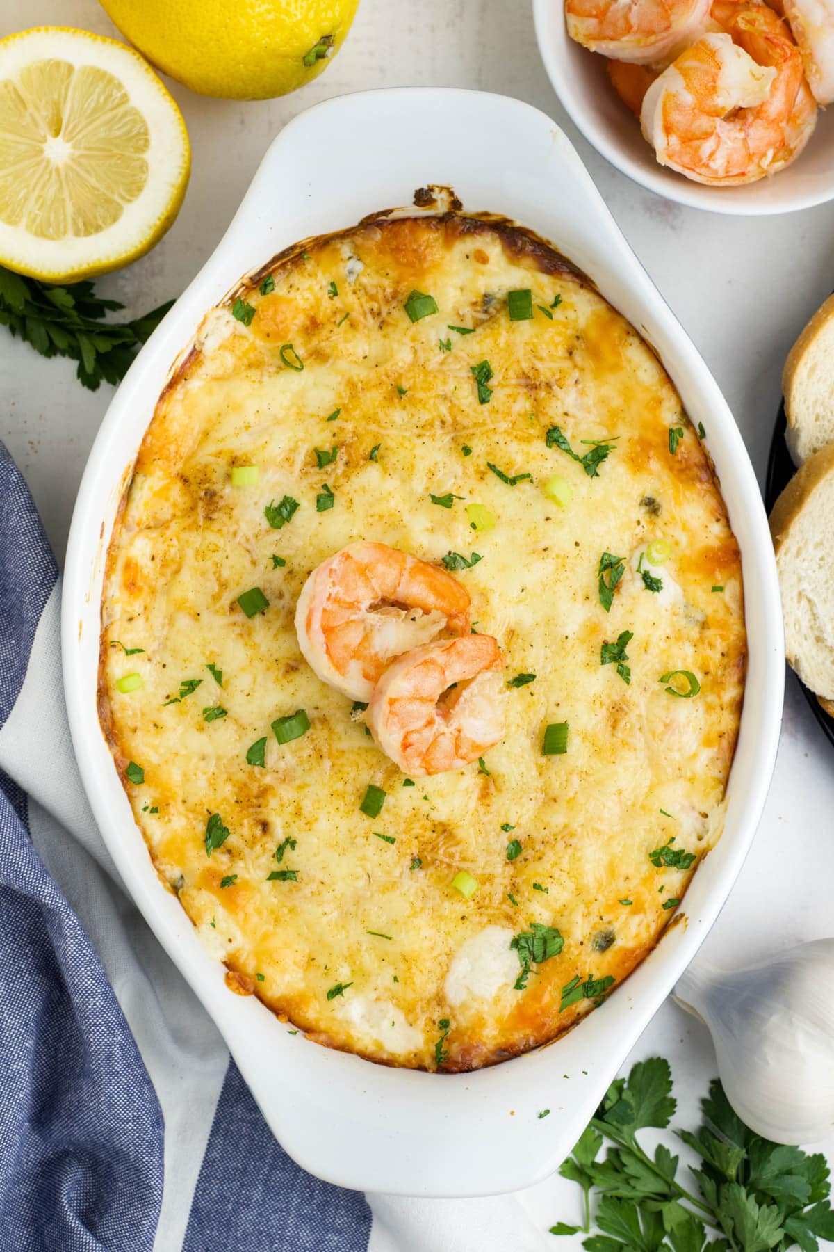 Baked shrimp dip in a white baking dish with whole shrimnp on top.