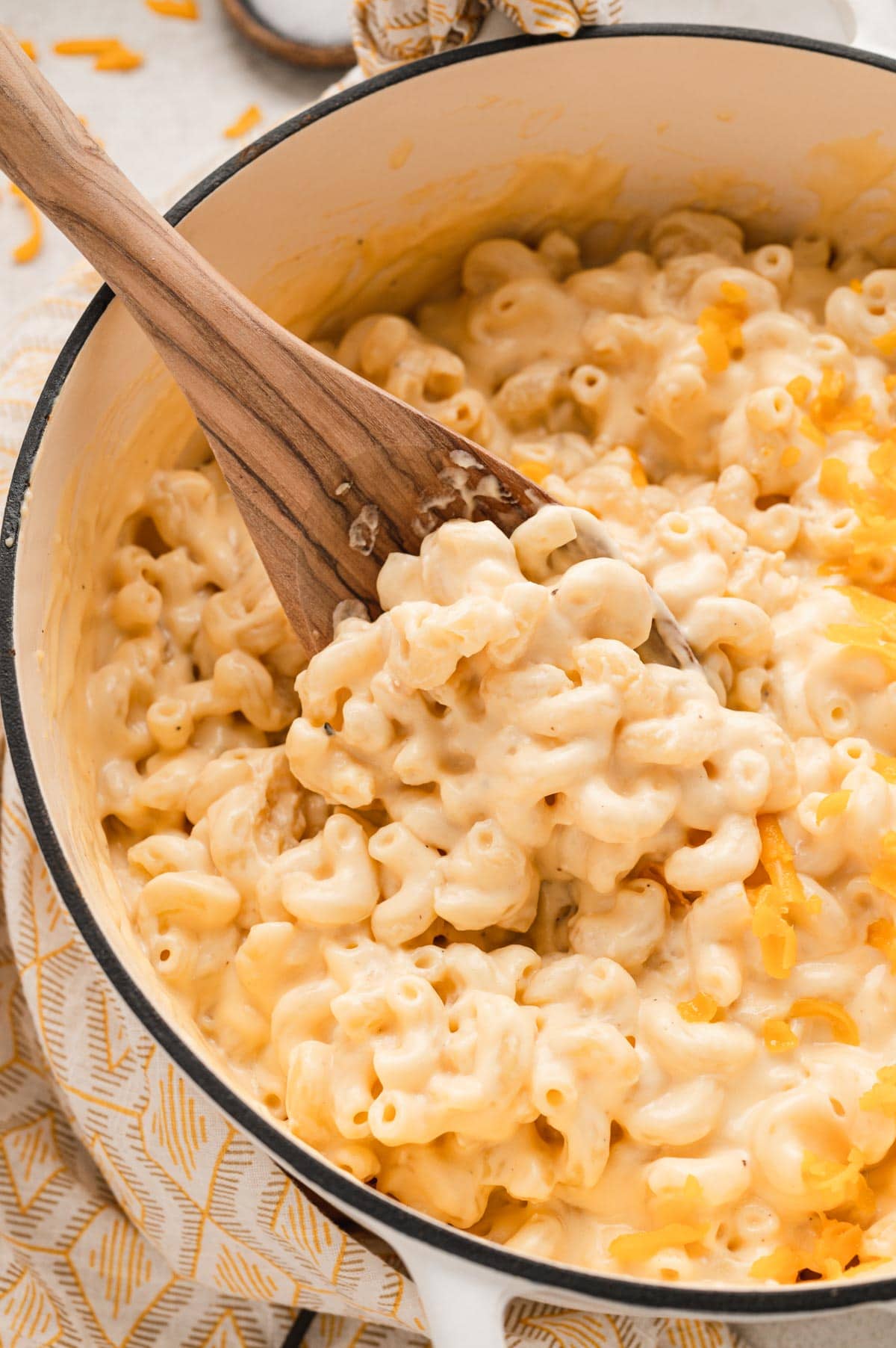 Macaroni and cheese in a large por with a woden spoon.