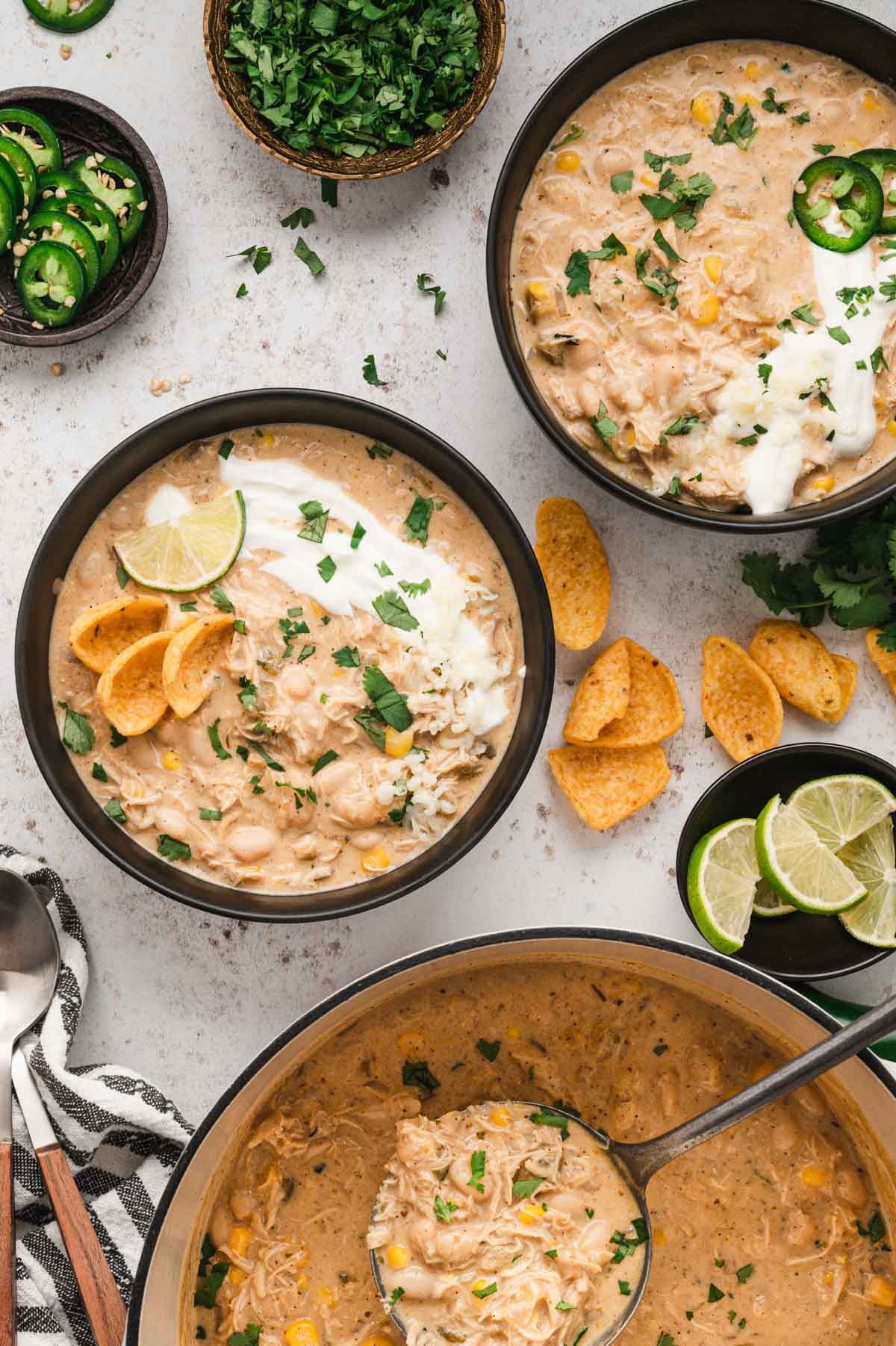 2 bowls of chicken chili soup with sour cream and corn chips.