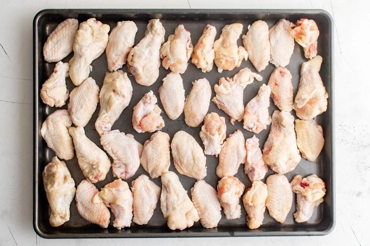raw chicken wings drying out on a baking sheet.