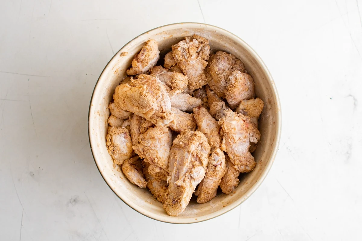 seasoned and floured chicken wings in a large bowl