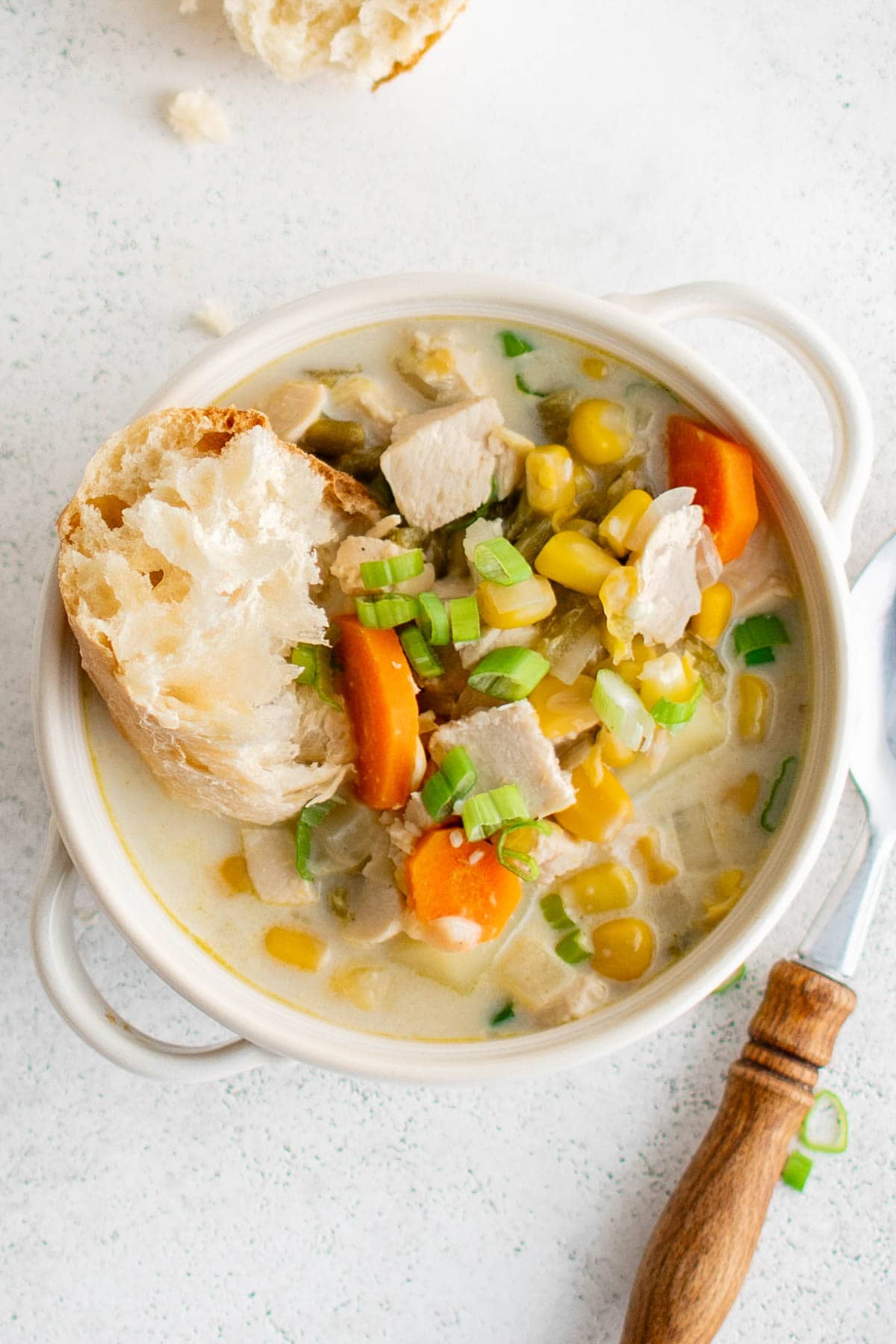 Bowl of creamy chicken soup with a pieces of bread.
