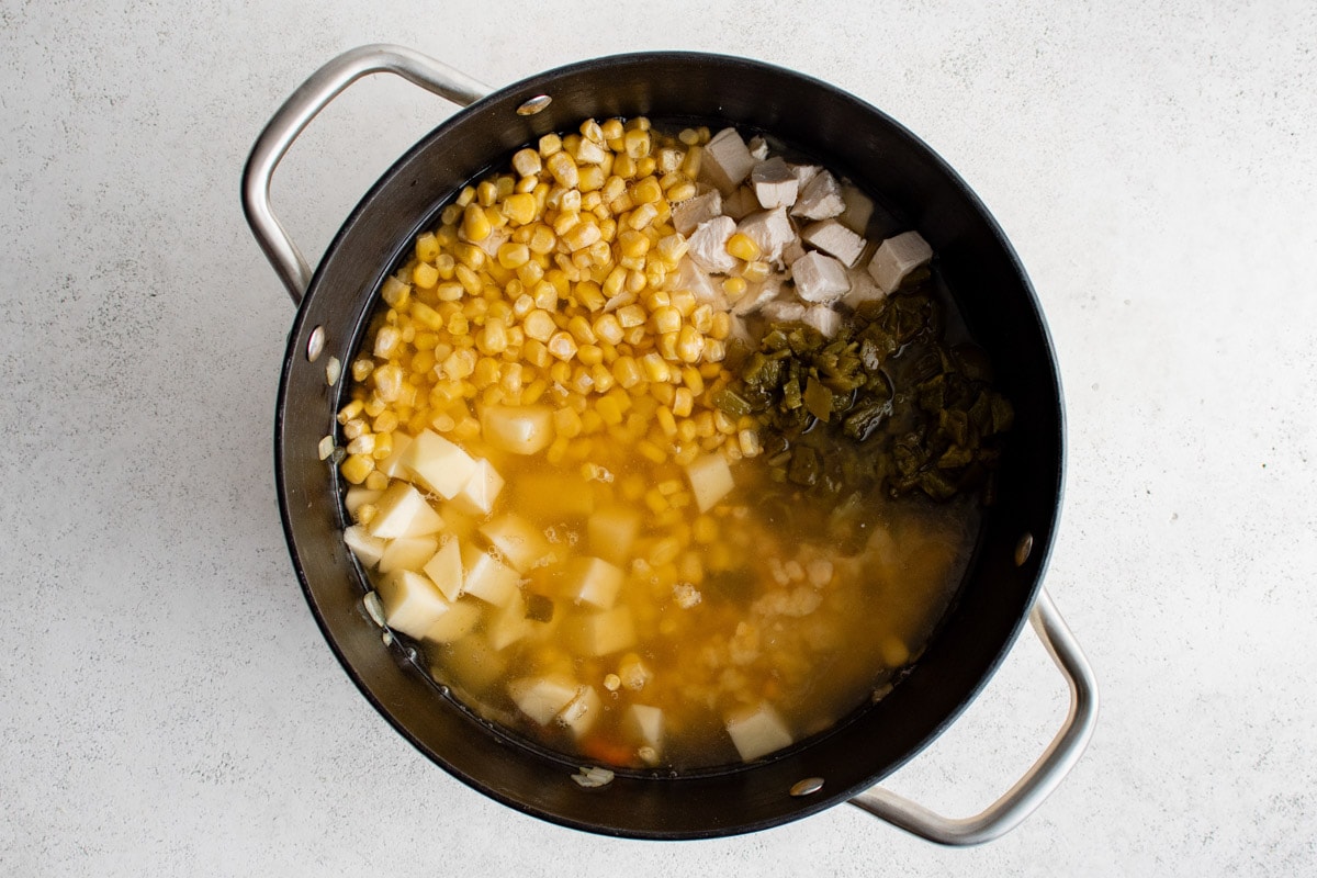 Broth, corn, chicken and green chiles added to the pot.