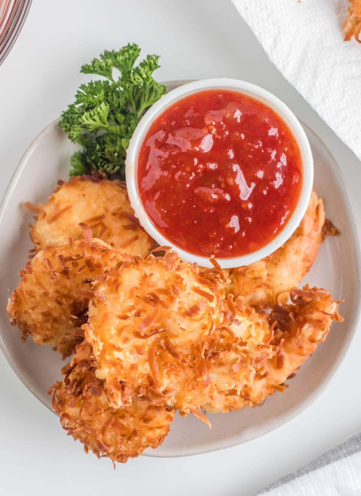 coconut shrimp on a platter with parsley and a dish of sauce