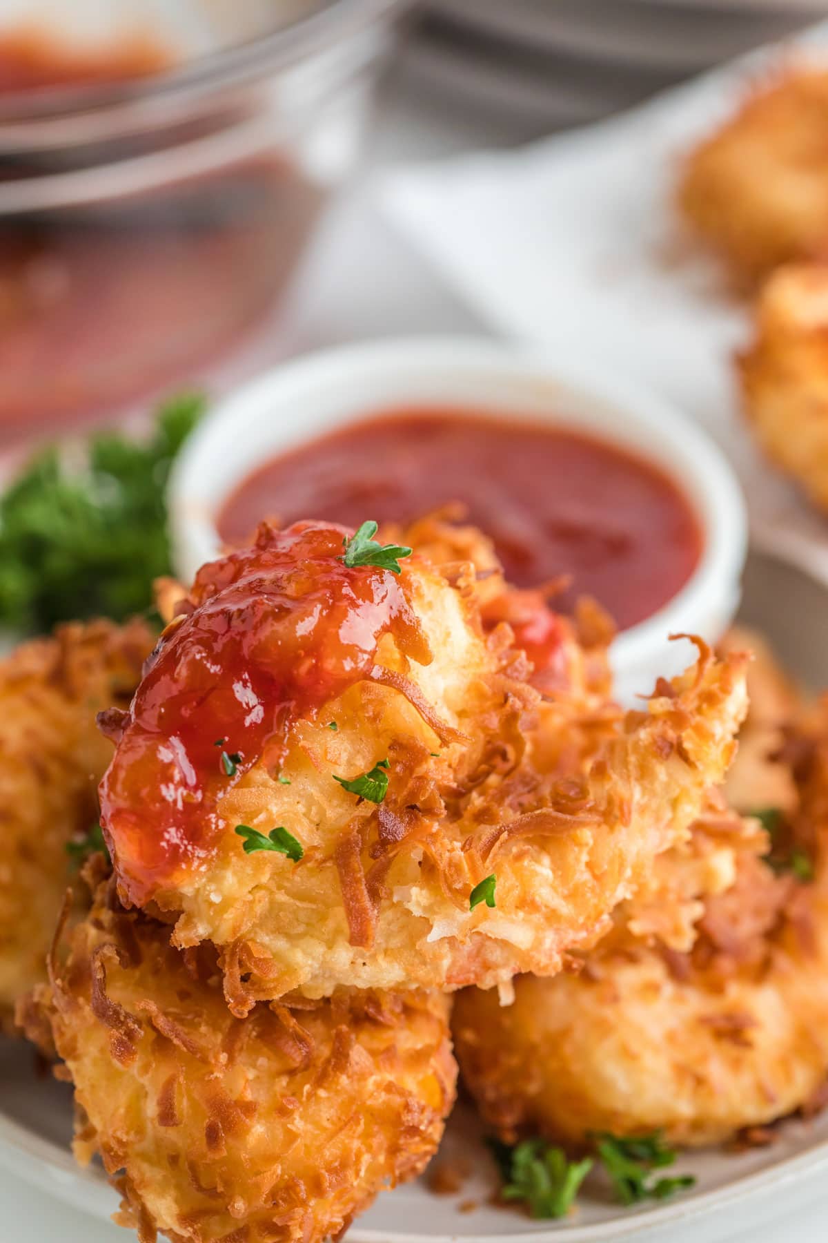 coconut shrimp on a platter with a dish of a red sauce.