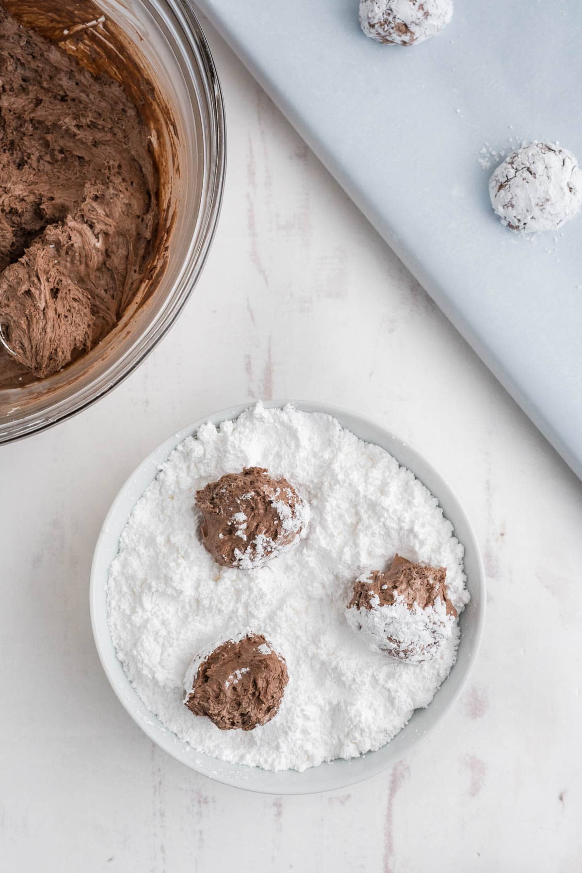 Dish of powdered sugar with balls of chocolate cookie dough.