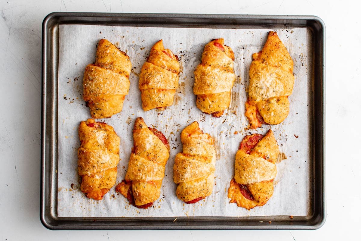 Baked pizza crescents rolls with pepperoni on a baking sheet. 
