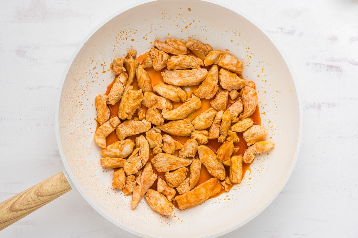 Cooked chicken breast pieces in a white skillet.