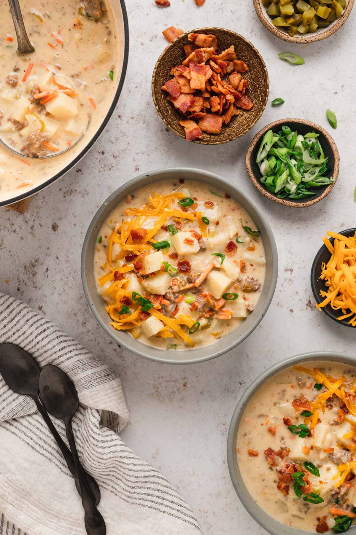 Soup bowl filled with cheeseburger soup and garnished with green onions, bacon and cheese.