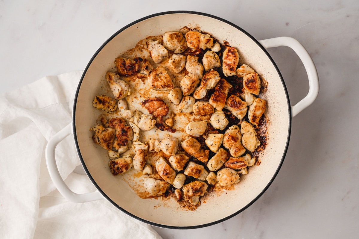 cooked chicken pieces in a white skillet.