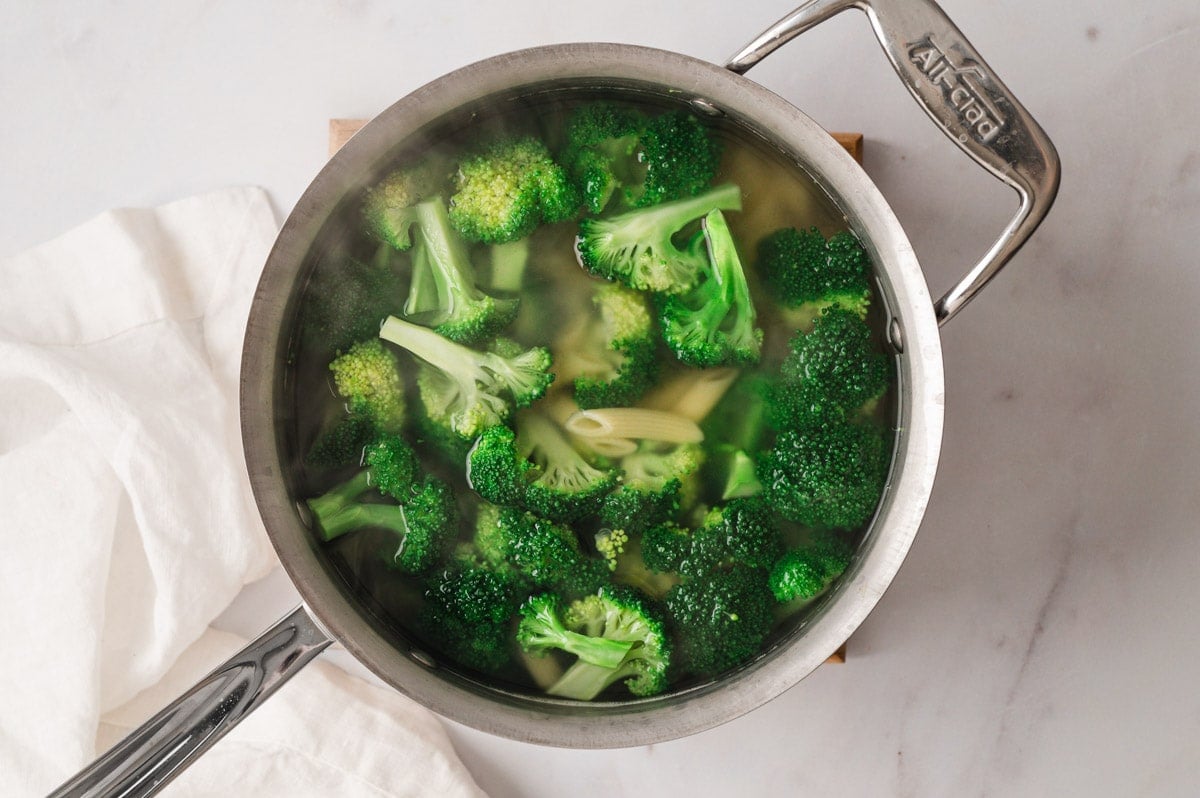 Broccoli and noodles in water in a large pot.