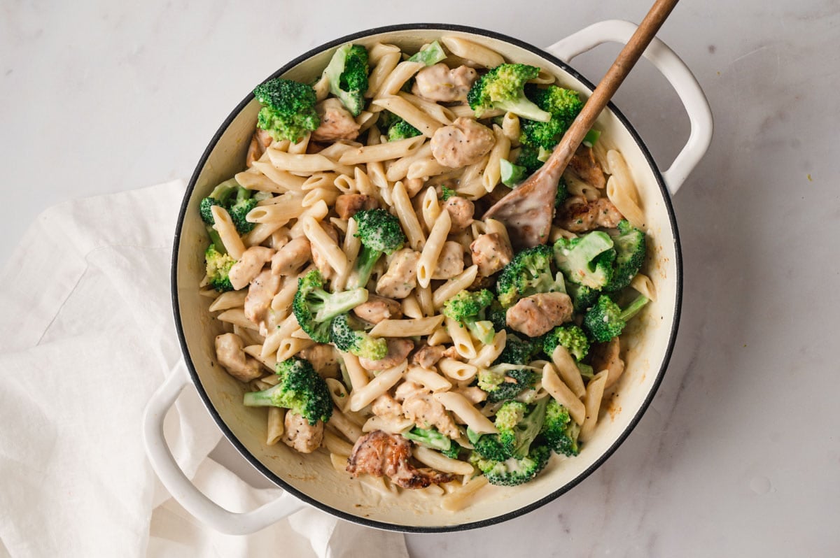 Broccoli, penne pasta, chicken pieces with a lemon cream sauce all mixed together in a skillet.