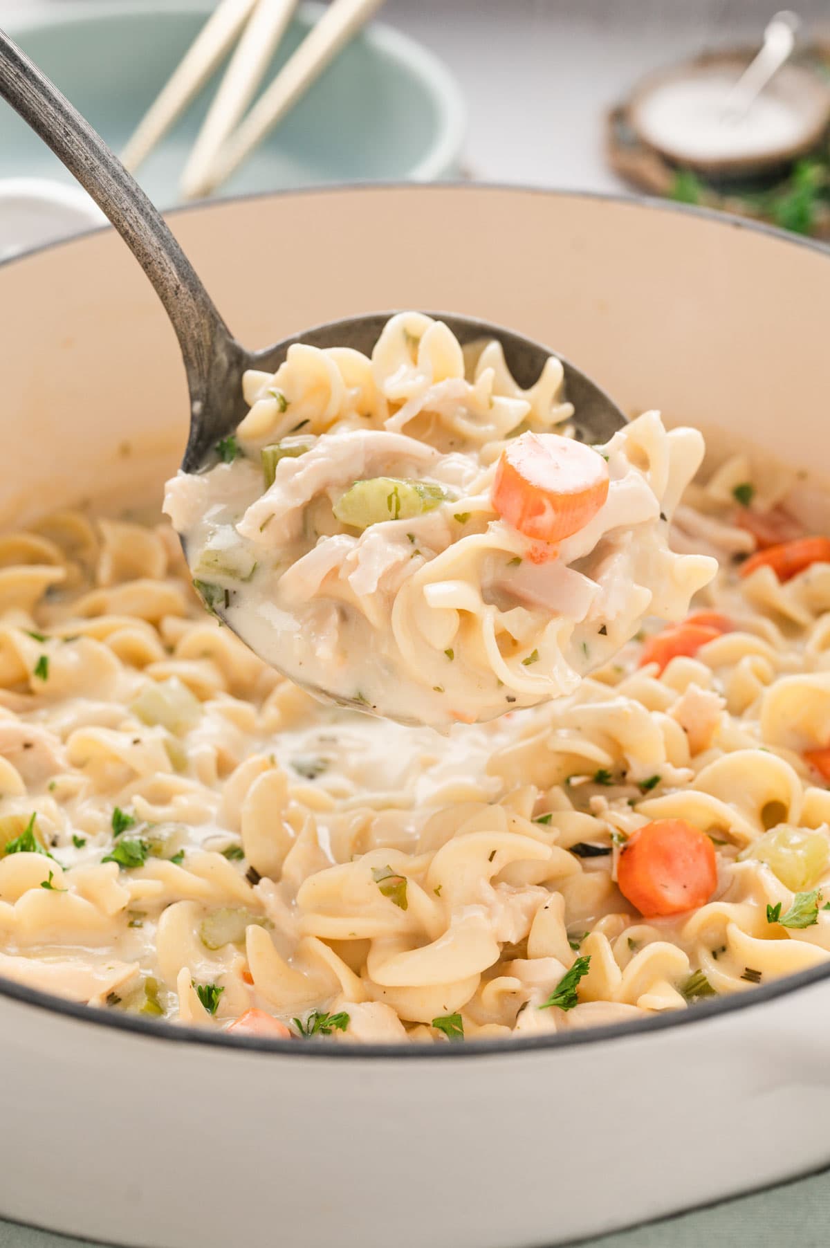 Pot of creamy chicken noodle soup witha a ladle.