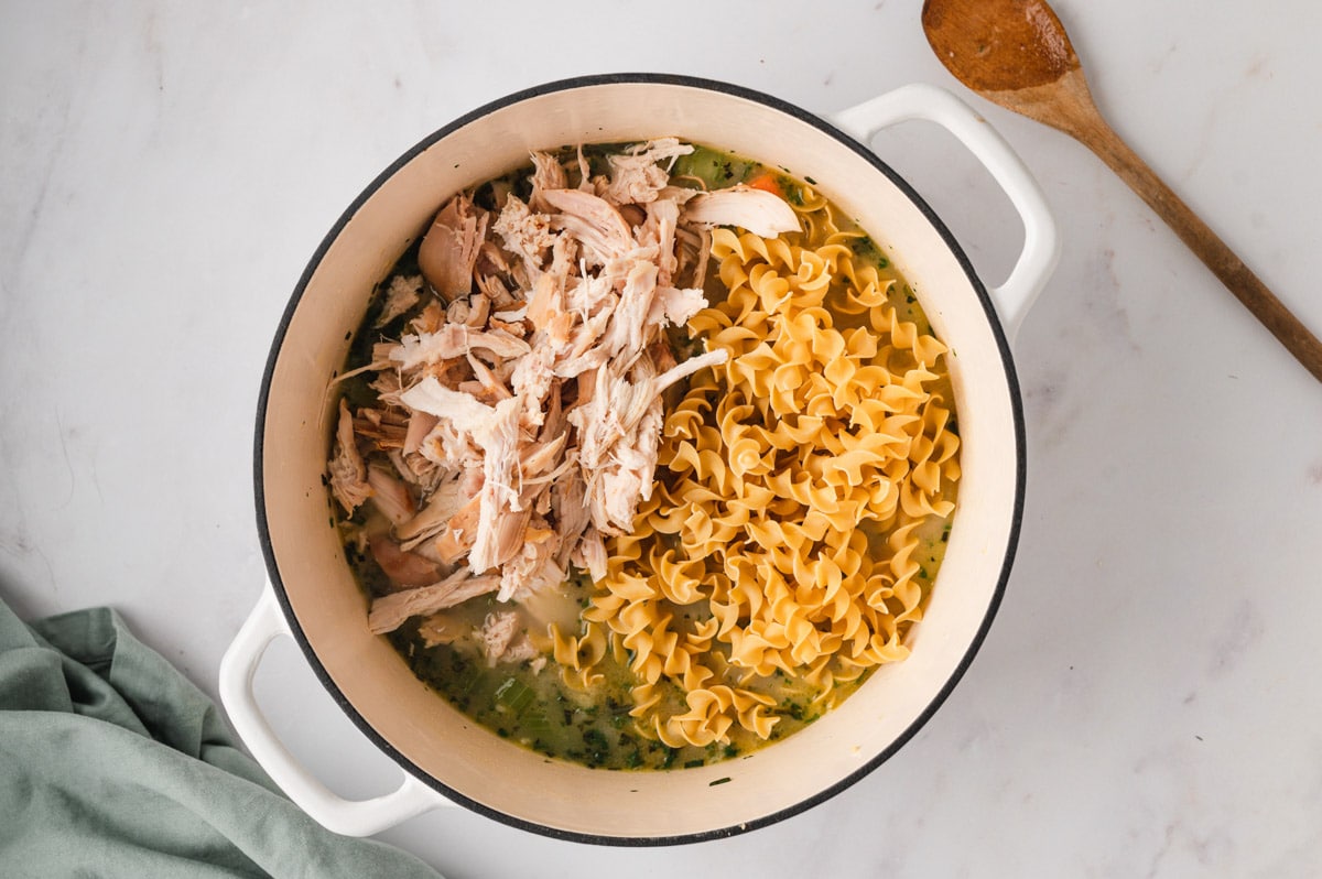 Shredded chicken and egg noodles in a large soup pot.