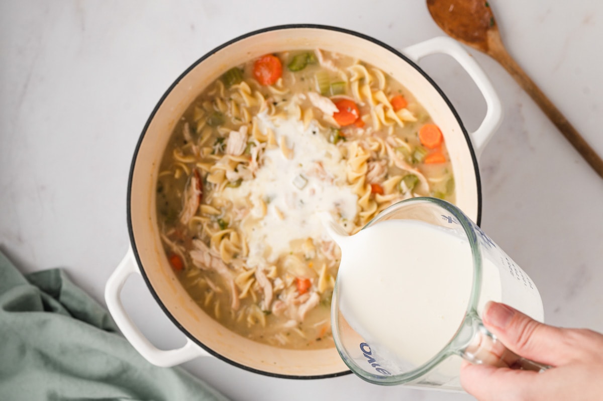 Chicken and noodles in broth with cream pouring in. 
