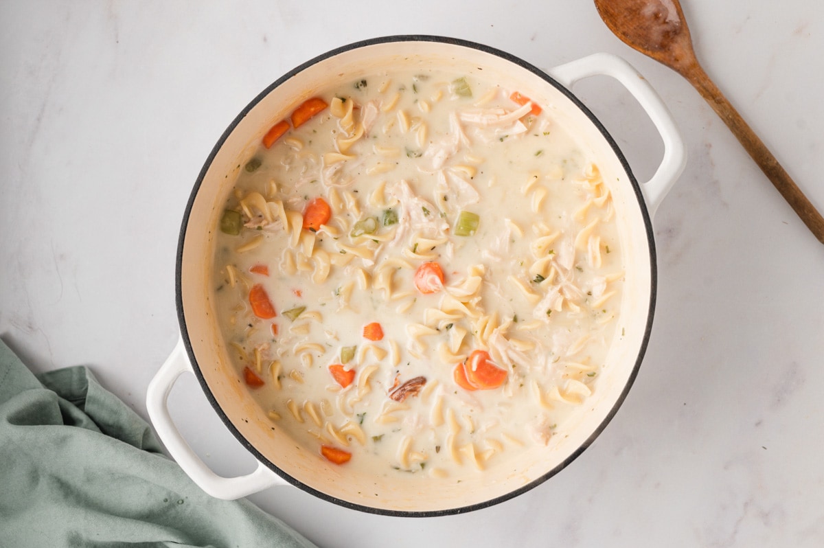 A large soup pot with creamy chicken noodle soup.