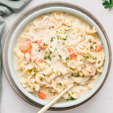 bowl of creamy chicken noodle soup with a spoon.