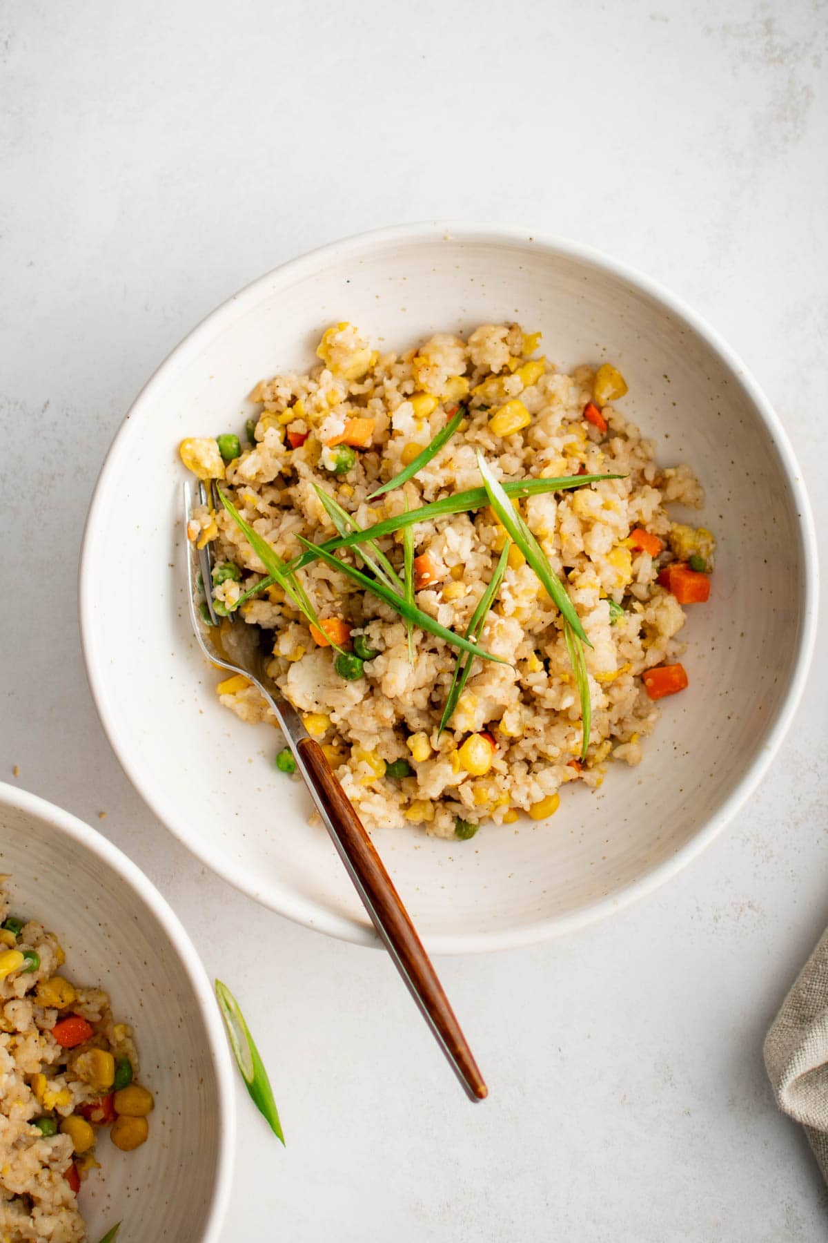 Fried rice in a white bowl with a wooden spoon.