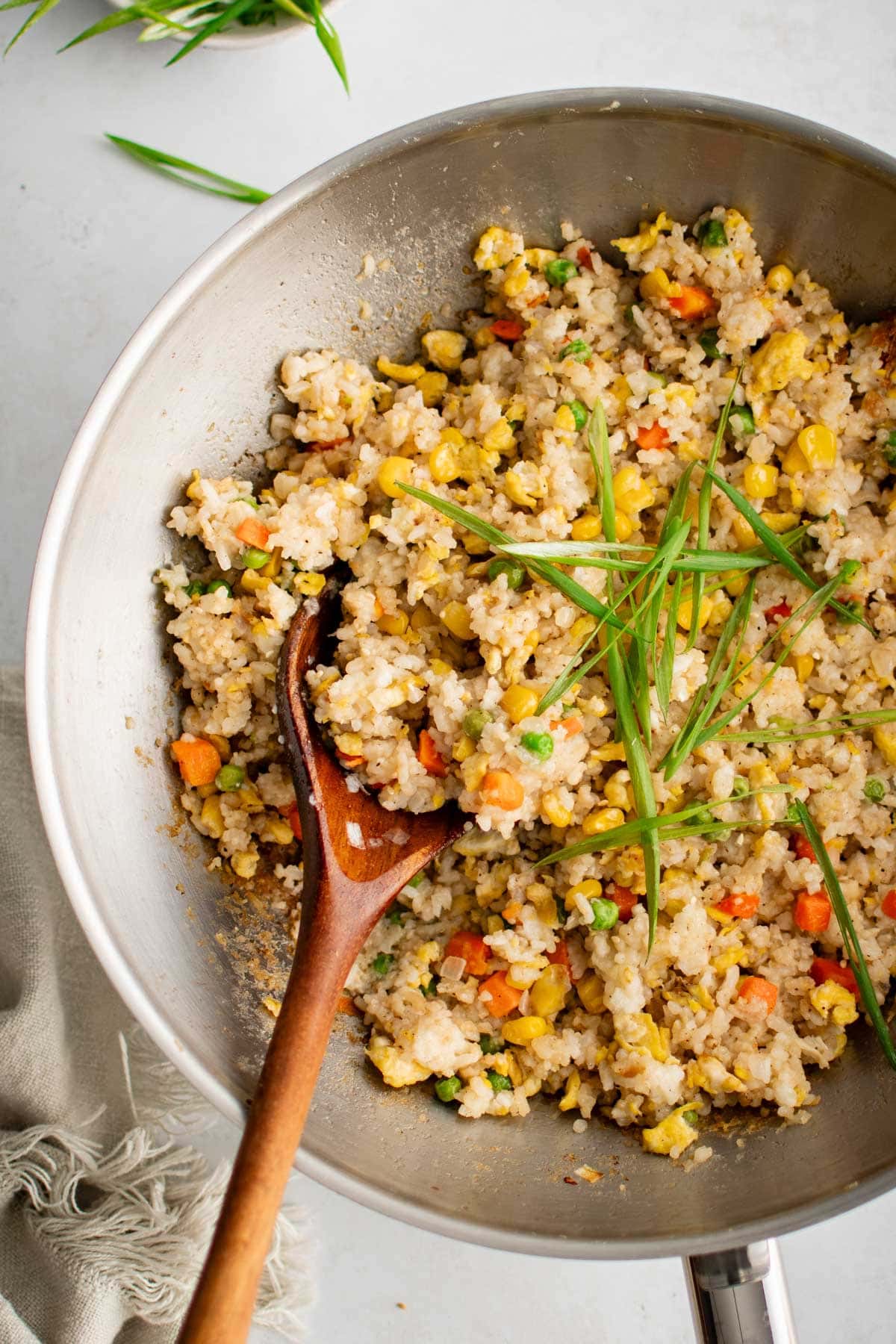 Fried rice in a wok with a wooden spoon.
