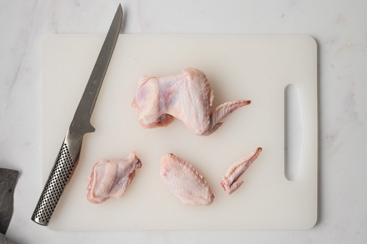 Chicken wings, a knife on a cutting board.