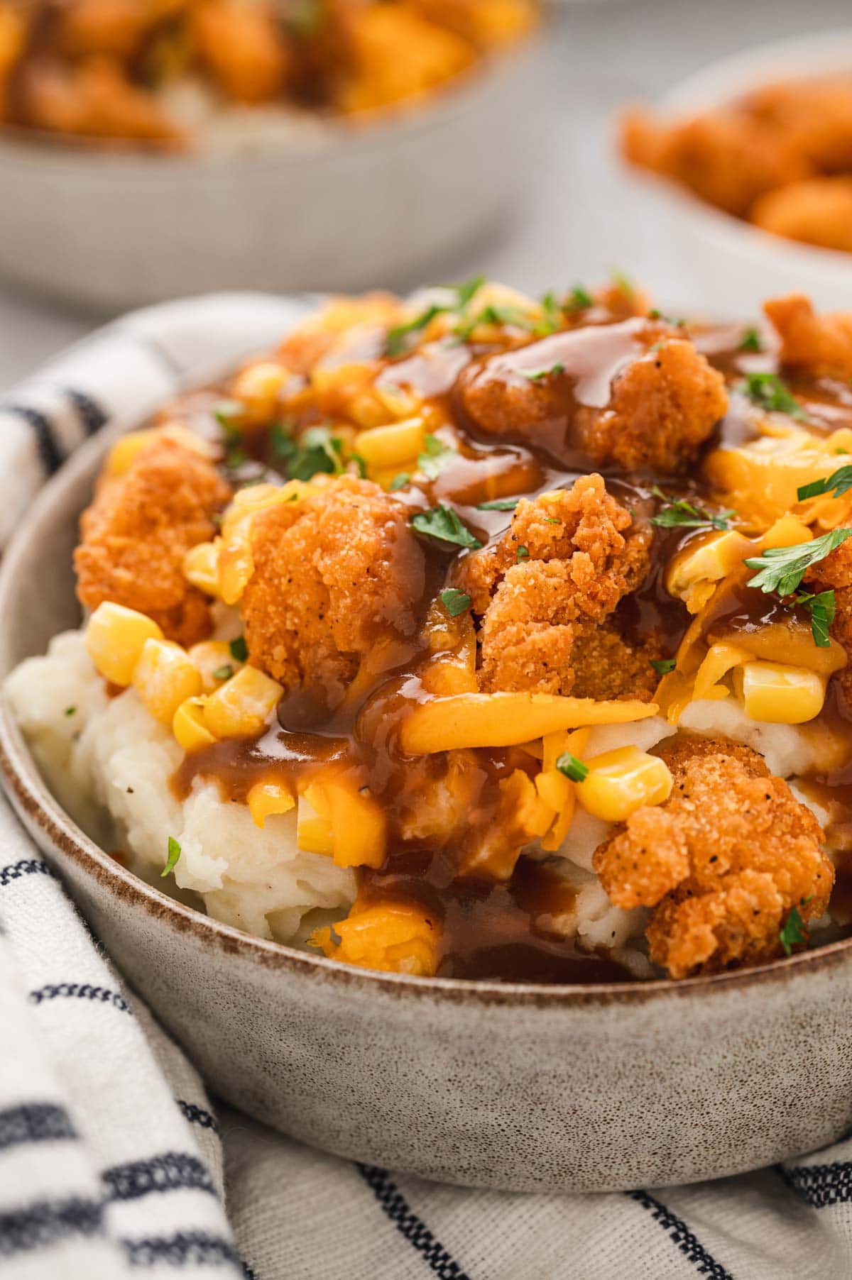 MAshed potatoes topped with corn, cheese, gravy adn popcurn chicken.