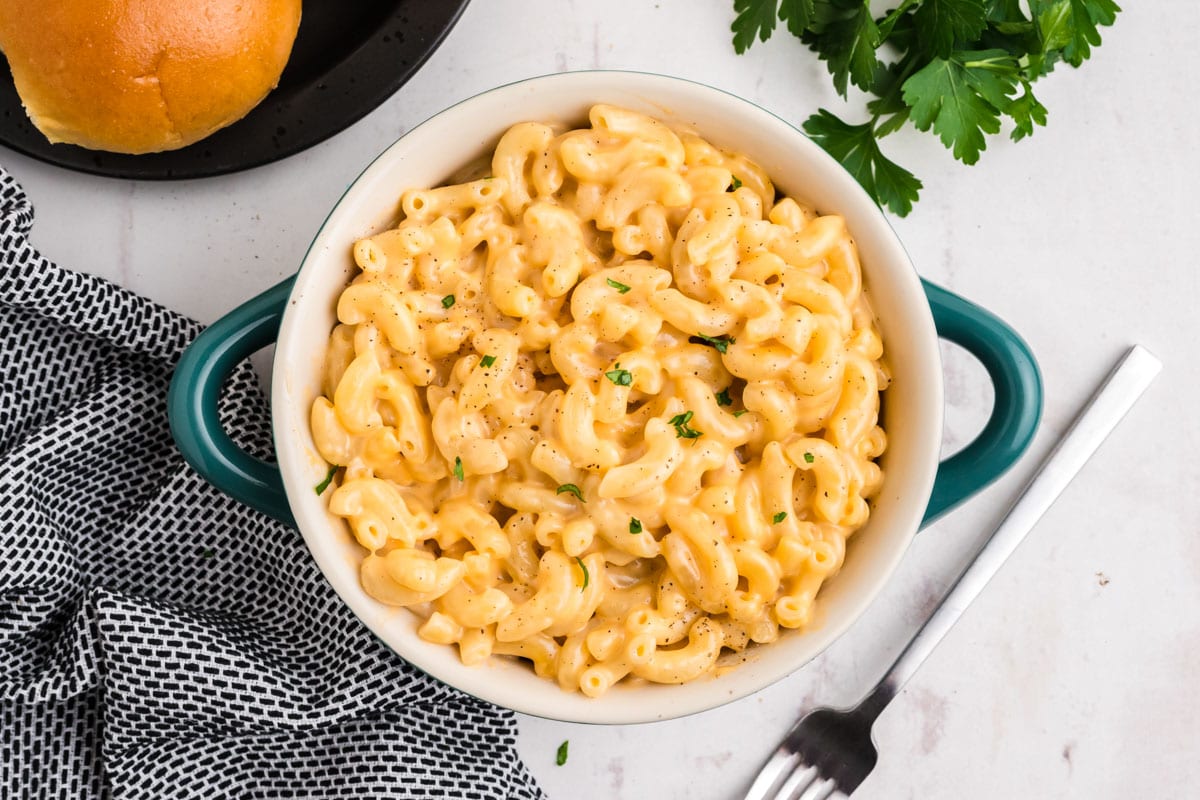 Creamy mac and cheese in a dish with blue handles and a fork.