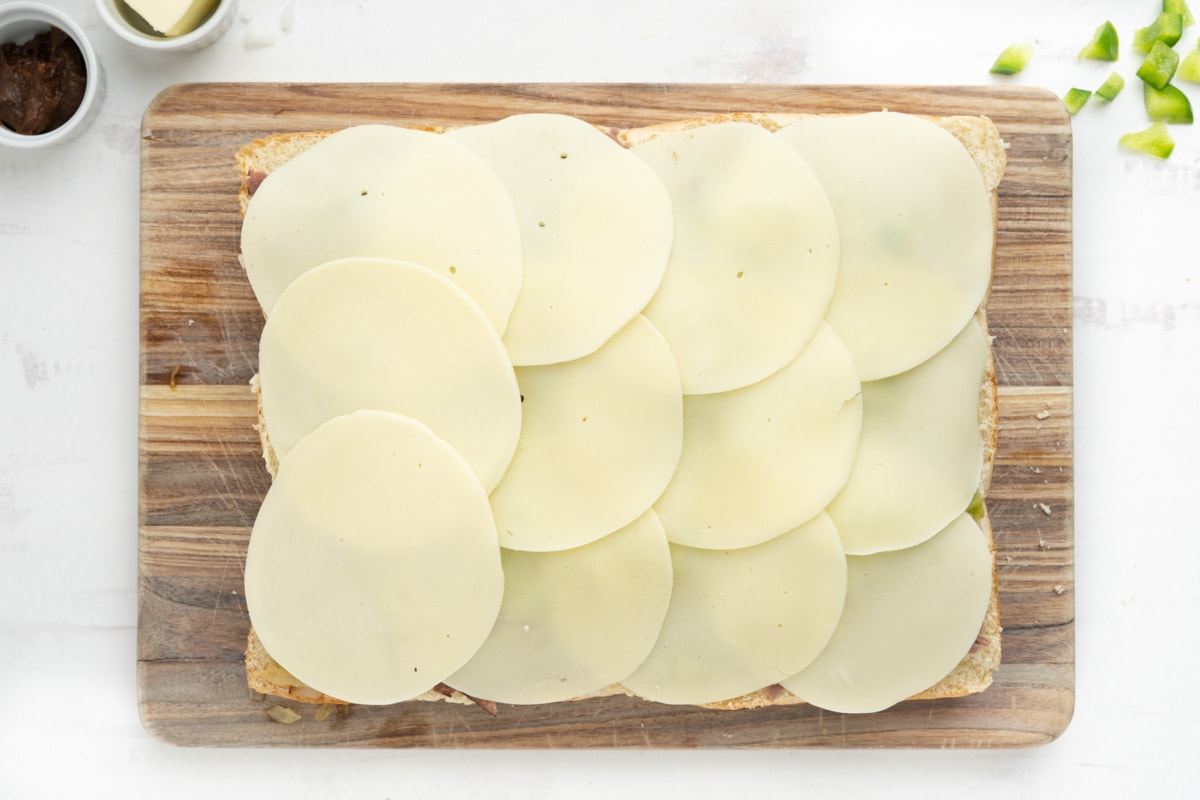 Sliced provolone cheese on a slab of rolls.