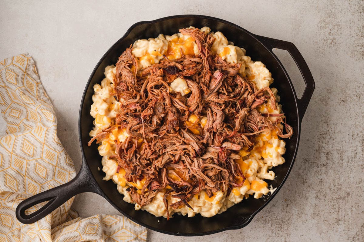 Pulled pork on top of mac and cheese in a cast iron skillet.