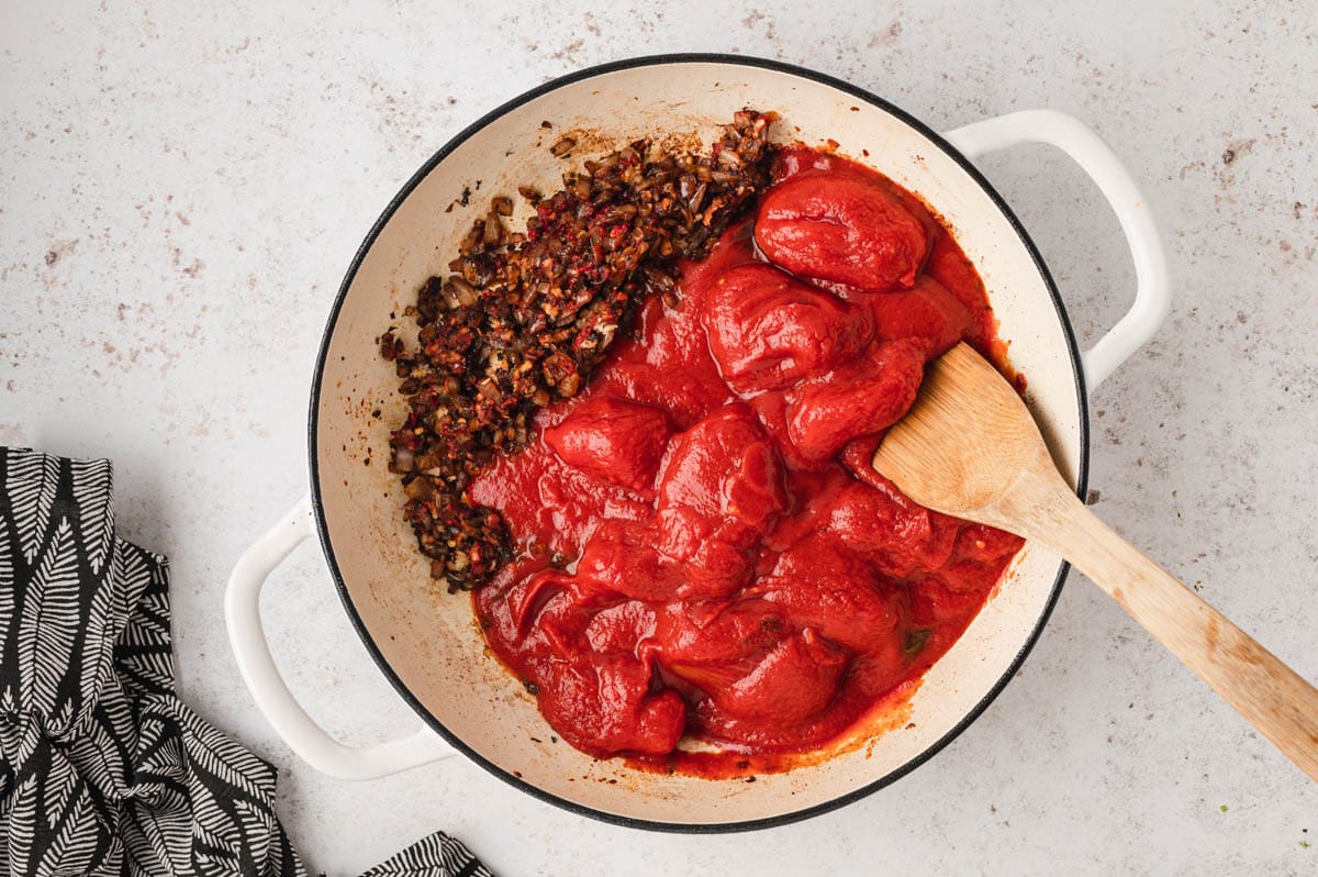 Browned onions and crushed tomatoes in a skillet.