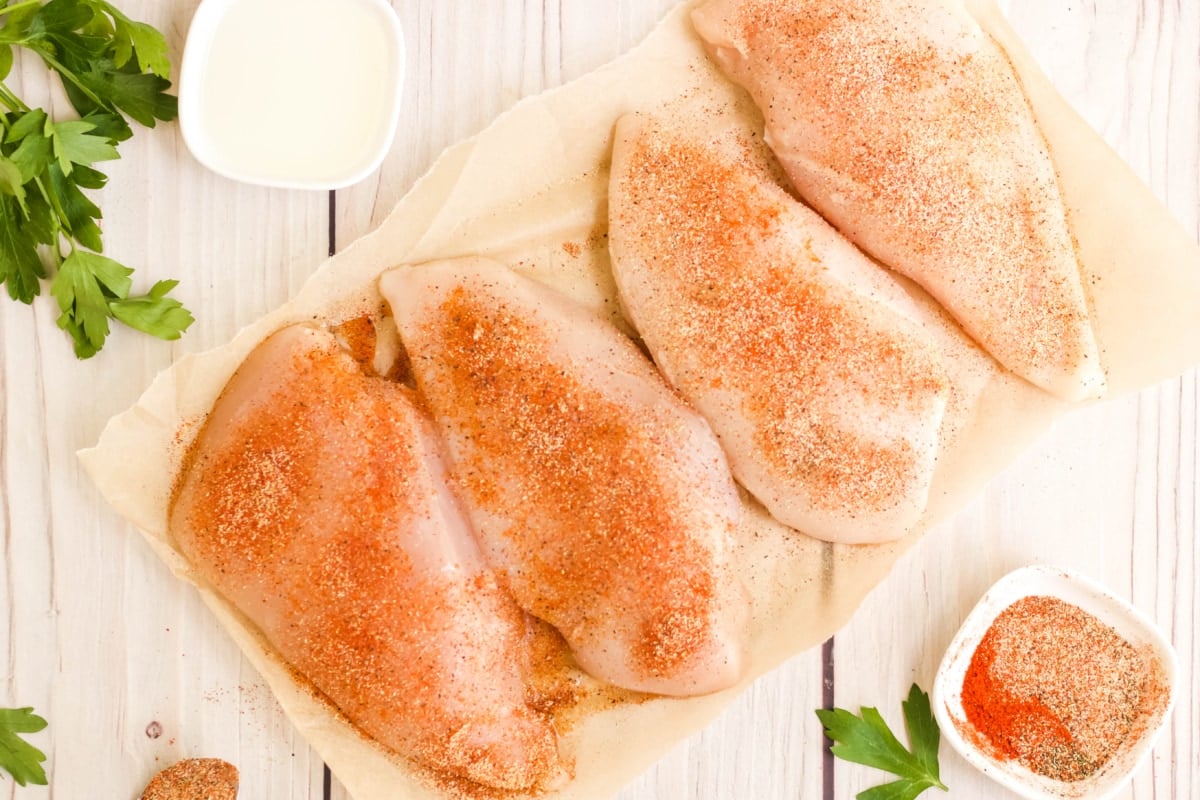 4 uncooked chicken breasts with seasoning.