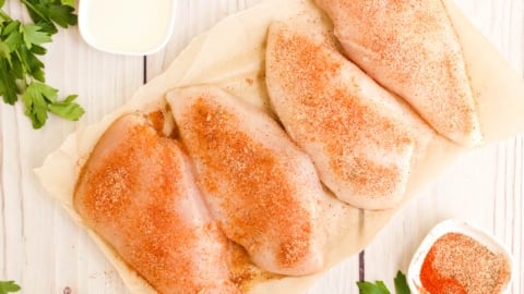 4 uncooked chicken breasts with seasoning.