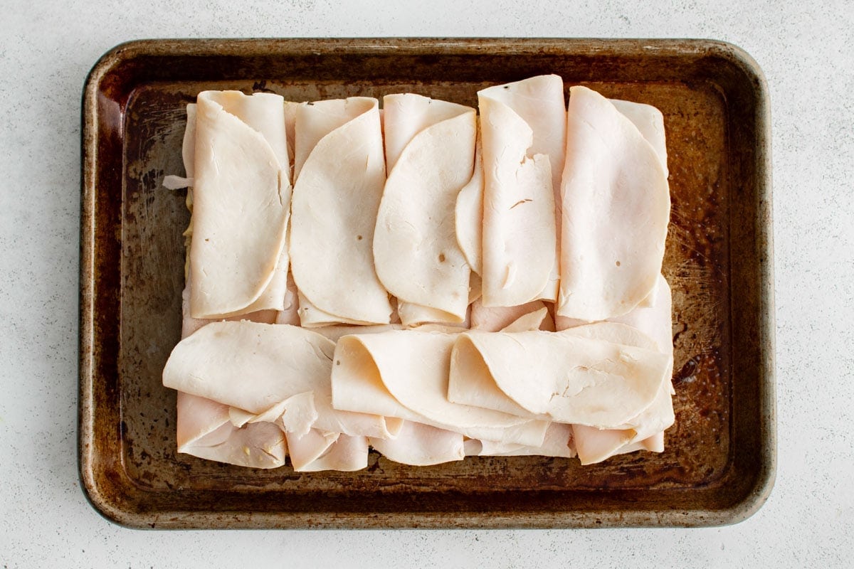 sliced turkey on a slab of hawaiian rolls