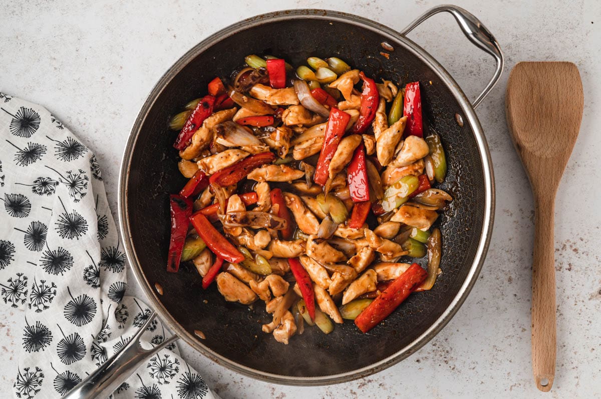 Chicken and vegetables in a brown sauce in a skillet.