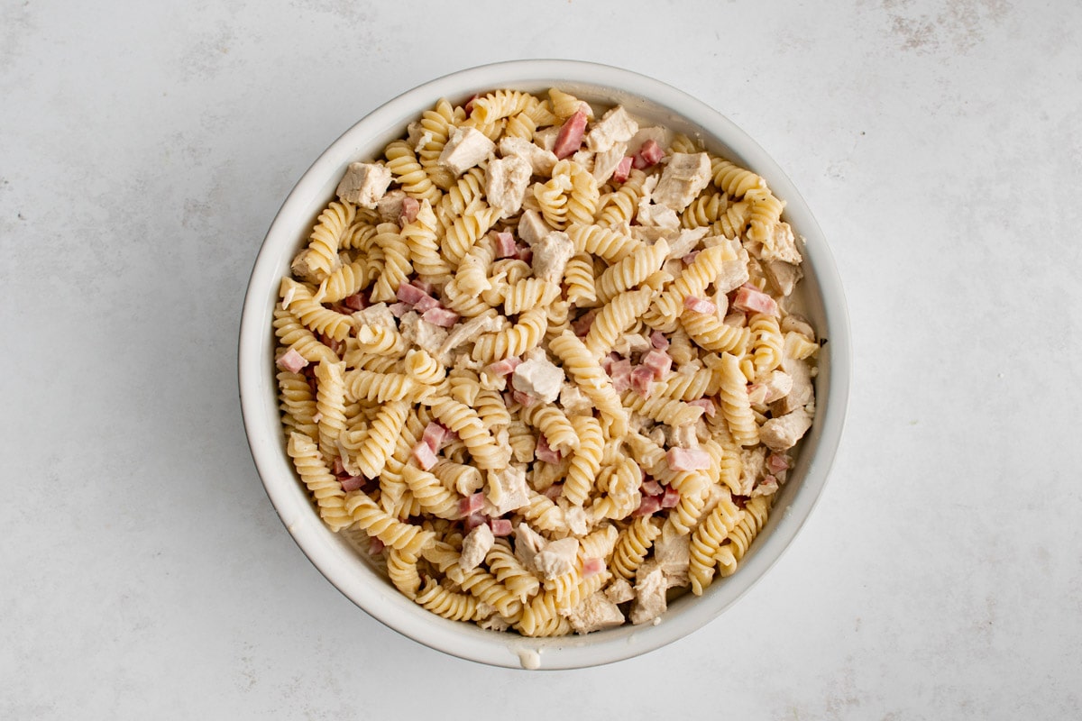 Chicken cordon bleu casserole with noodles, ham and chicken in a white baking dish.