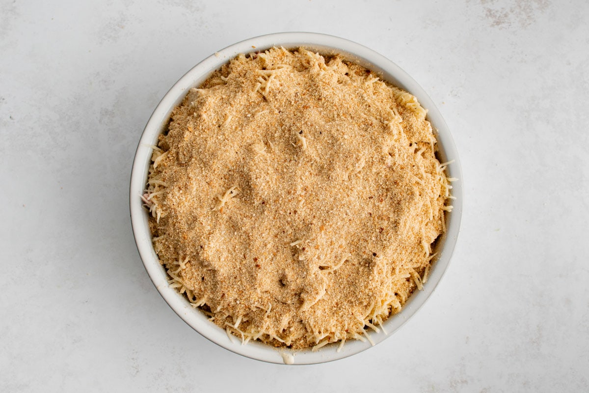 Breadcrumbs and shredded cheese on top of a casserole in a baking dish.