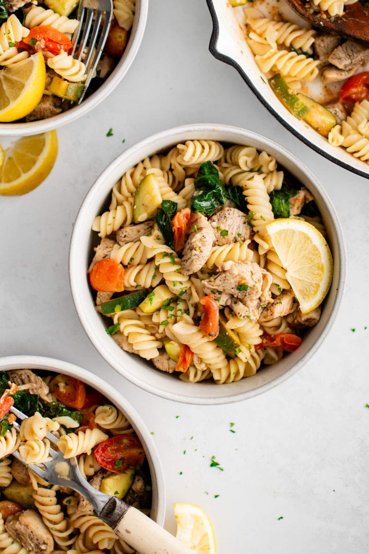 Small bowl with rotini pasta, veggies and a lemon slice.