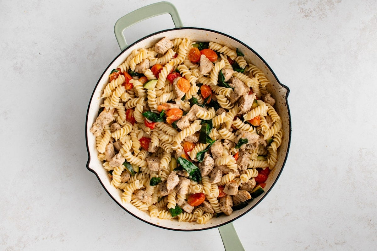 Chicken and pasta with veggies in a skillet.
