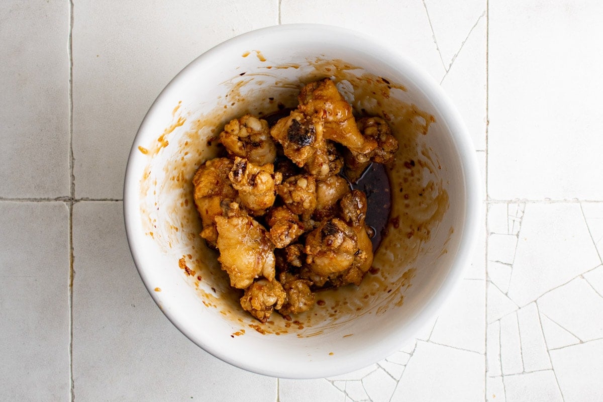 Chicken drumettes in a bowl with sauce poured over them.